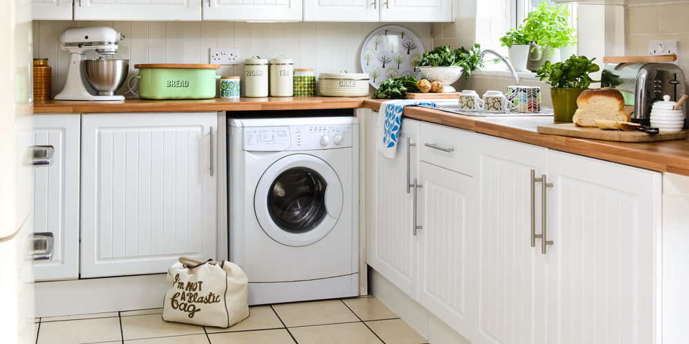 White kitchen with wooden counter tops and beige floor tiles