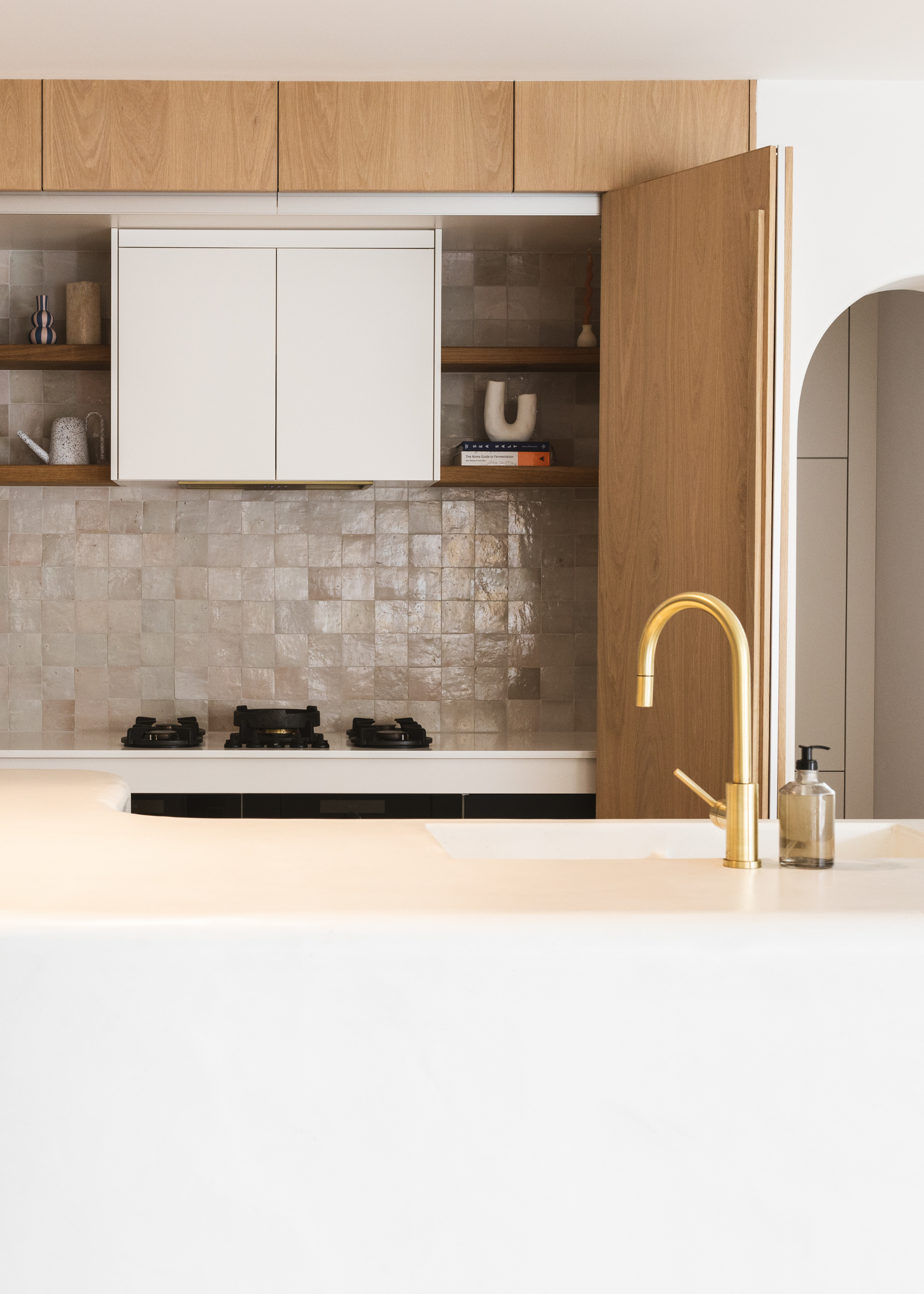 A small kitchen with doors, a large white island and a tile backsplash