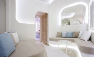 A futuristic hotel sitting room with two curved brown sofas, white metal round coffee table, wooden patterned cupboard and curve patterned floors.