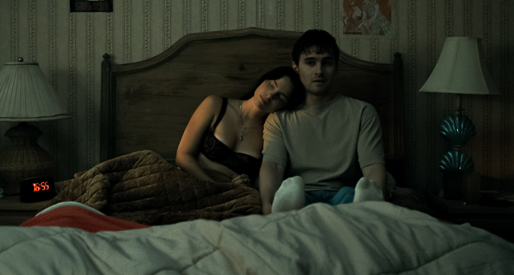 nikki rests her head on bear in bed as he looks scared in a still from obsession