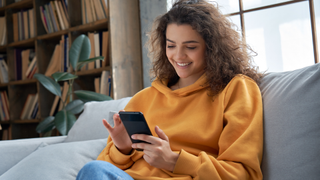 hispanic teen girl checking social media holding smartphone at home.