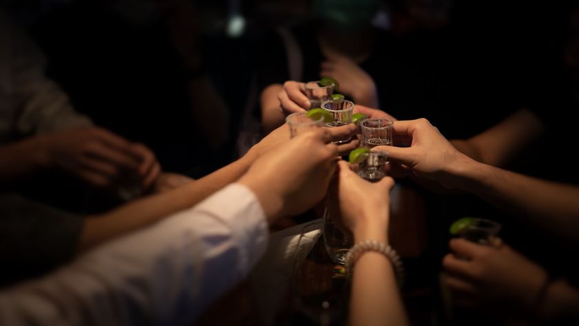 a group of people holds up shot glasses