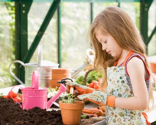 young girl in greenhouse growing cress in a pot
