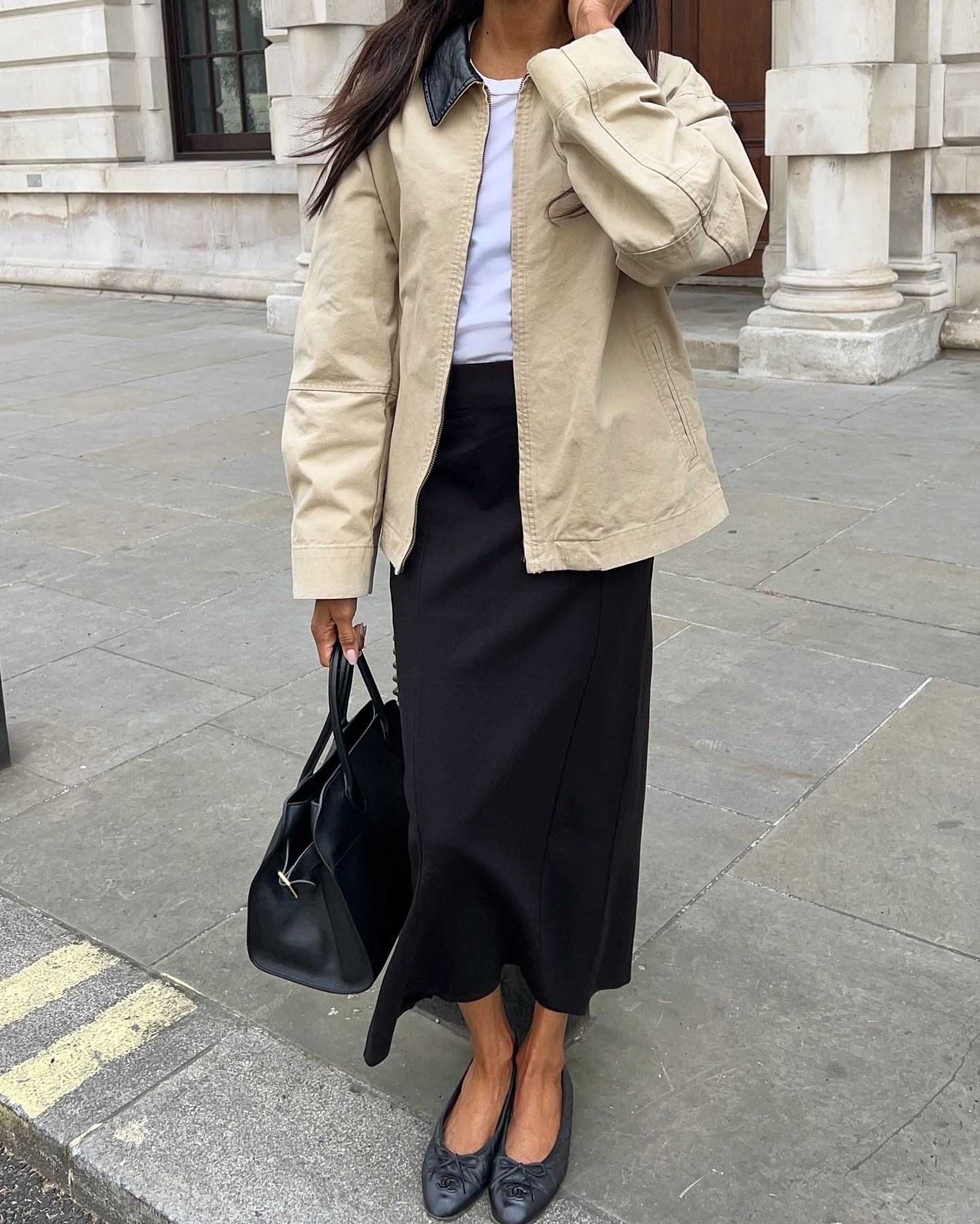 Woman in black skirt, barn jacket, and black ballet flats