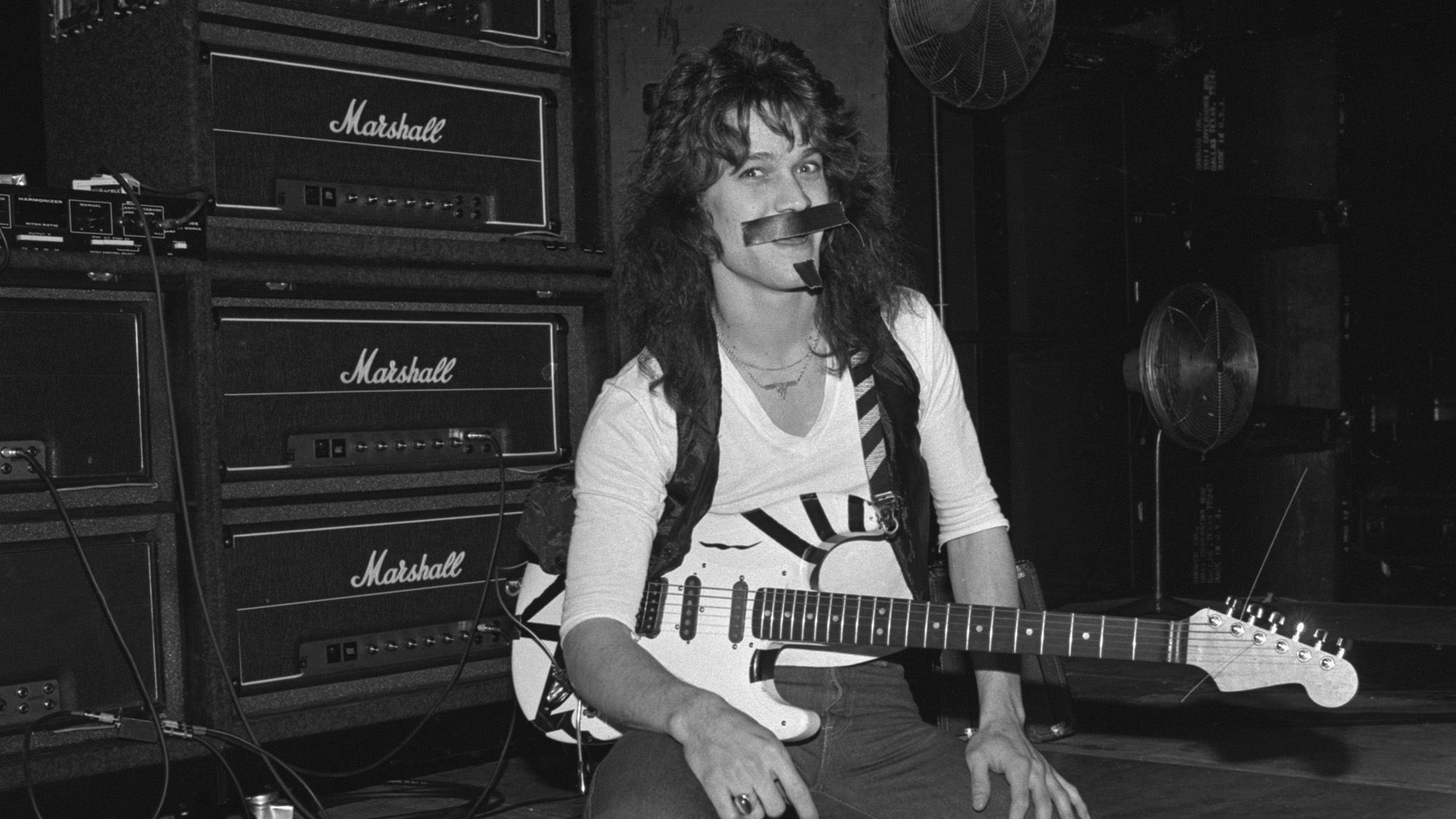 Eddie Van Halen holding his guitar in front of a stack of Marshall amps, 1978.