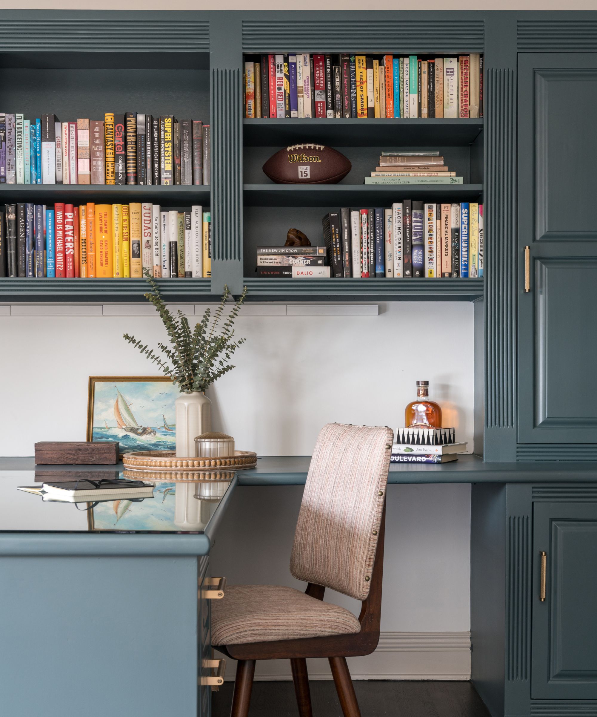 A home office with dark blue bookshelves and a desk
