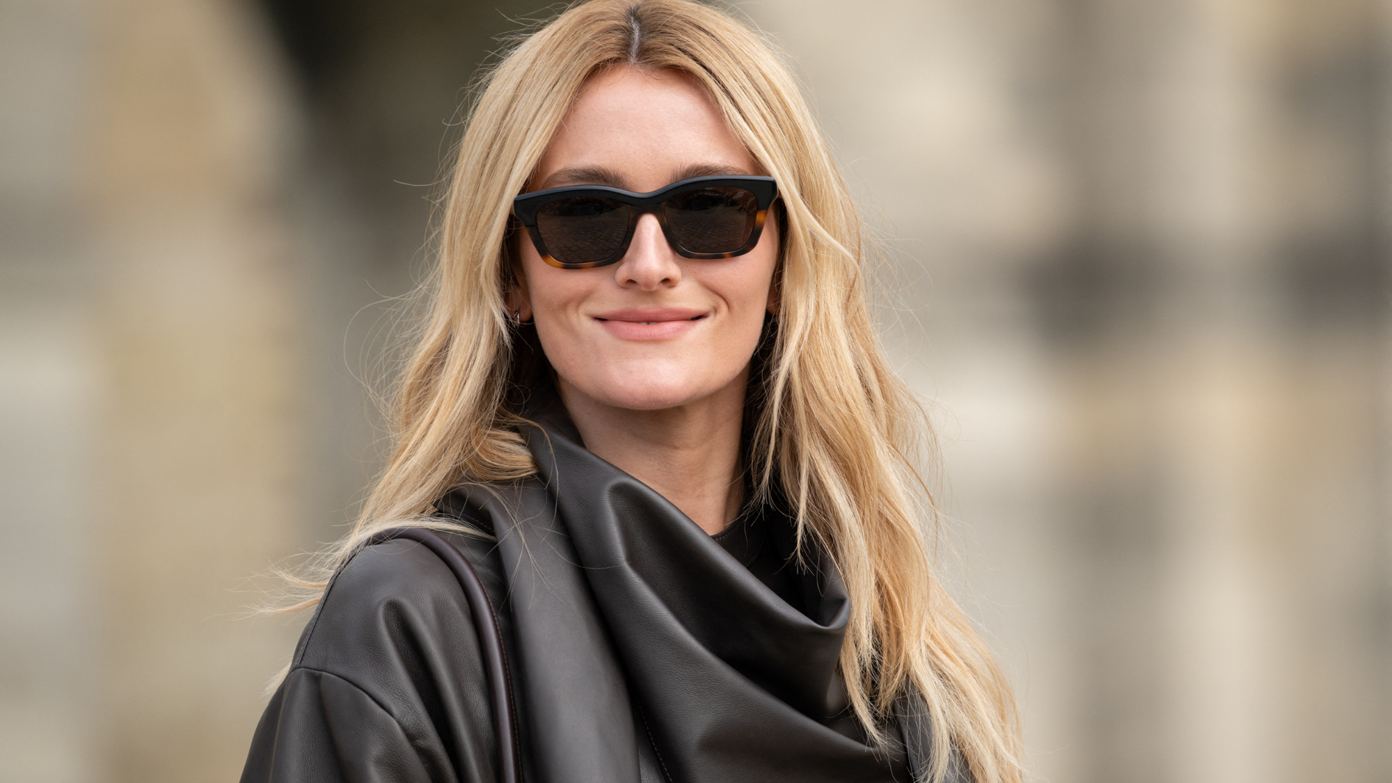 Sarah pidgeon sporting the Buttercream blonde trend on the street wearing a black leather top and black sunglasses