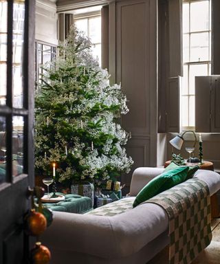 White tipped christmas tree in living room with grey button back sofa