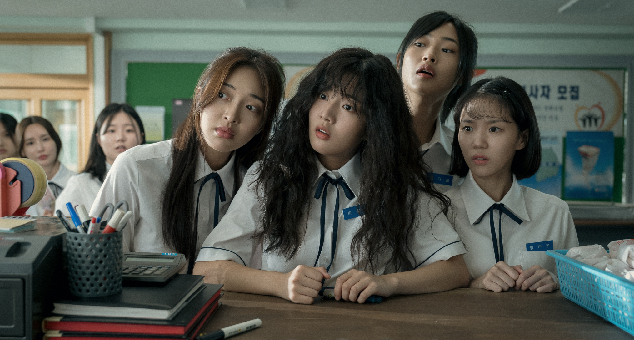 four school girls including in uniform including Shin Eun-soo as Park Se-ri sit at a desk and look to the right in a still from the movie love untangled