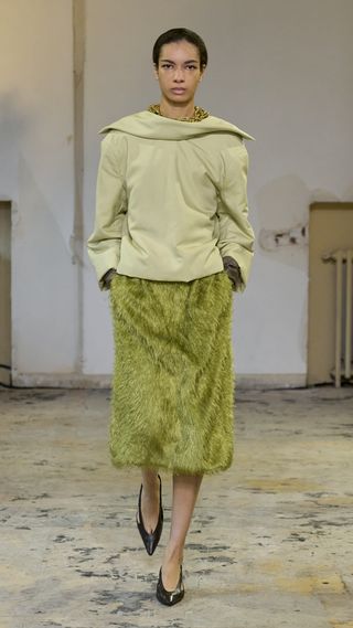 Carven fall/winter 2024 look featuring a green top and green skirt with court shoes.