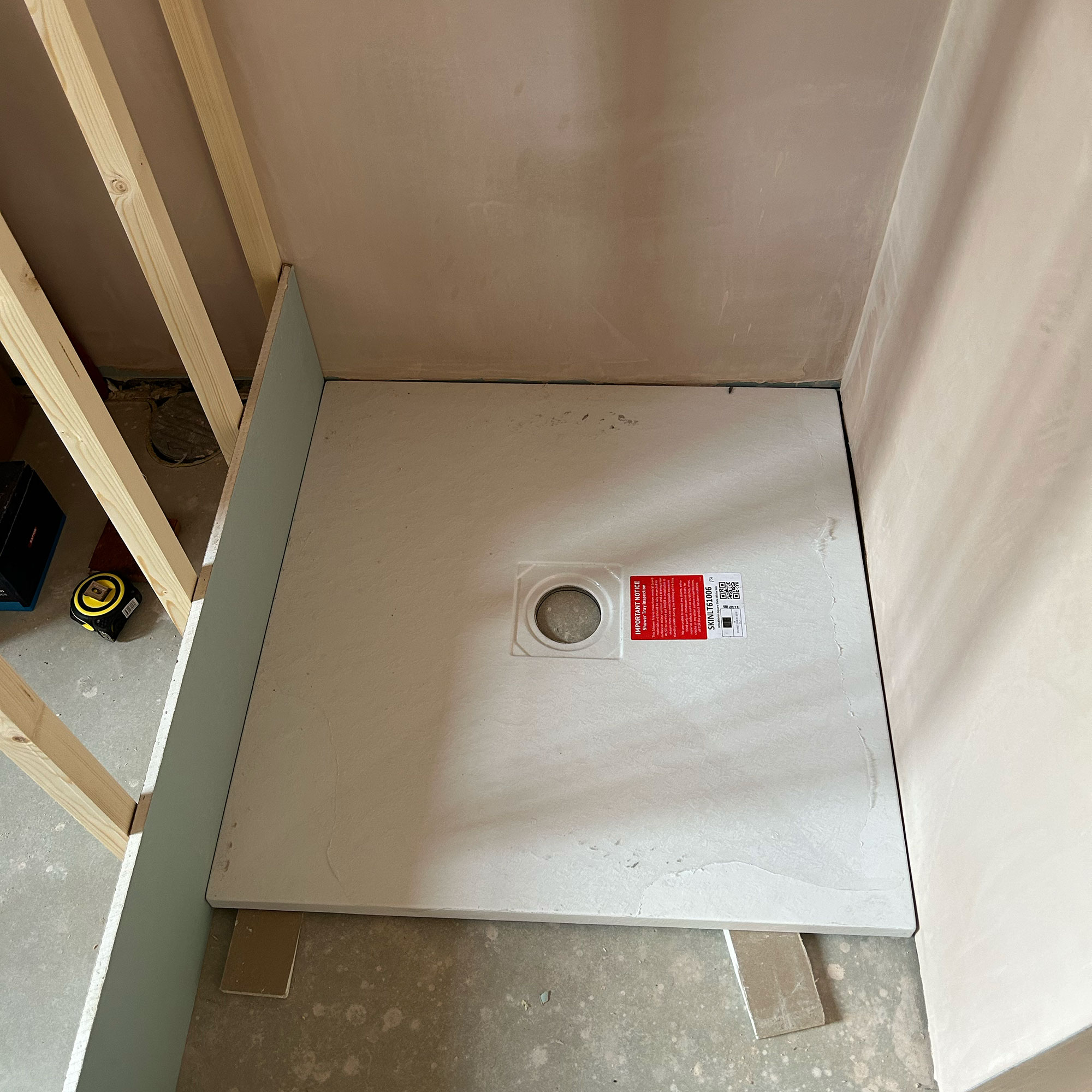 Shower tray being put into place in bathroom in the midst of being built