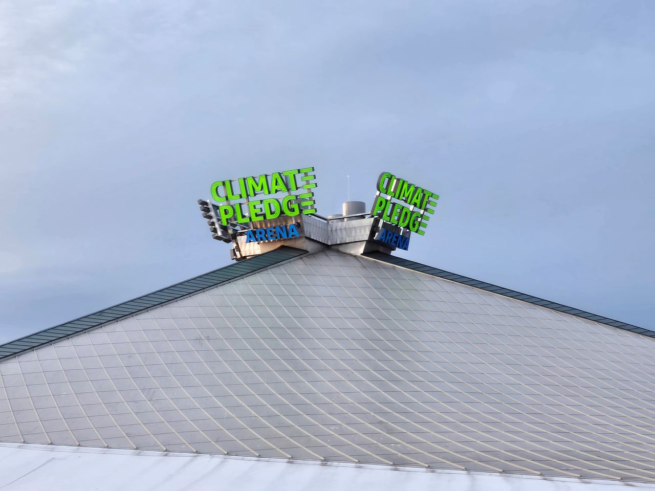 A neon sign on top of a building that reads "Climate Pledge Arena" at 4x zoom