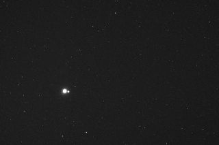 Earth and moon appear as two small bright dots against a backdrop of stars.
