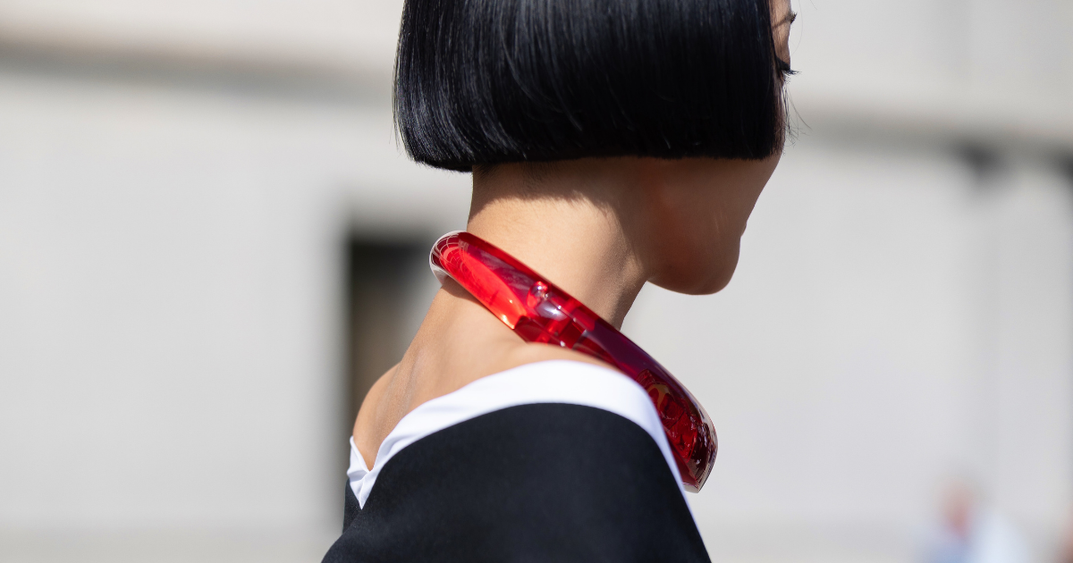 Dramatic haircut: bob haircut Kiwi Lee is seen wearing short bob cut hair, a red necklace, a black and white long sleeves top with a red pin,