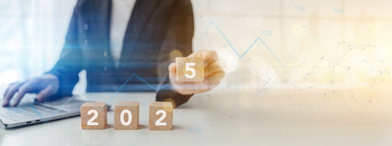 Businessman holding square wooden blocks with numbers showing the number 2025