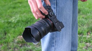 Sony A7CR camera held in a hand by a person's side