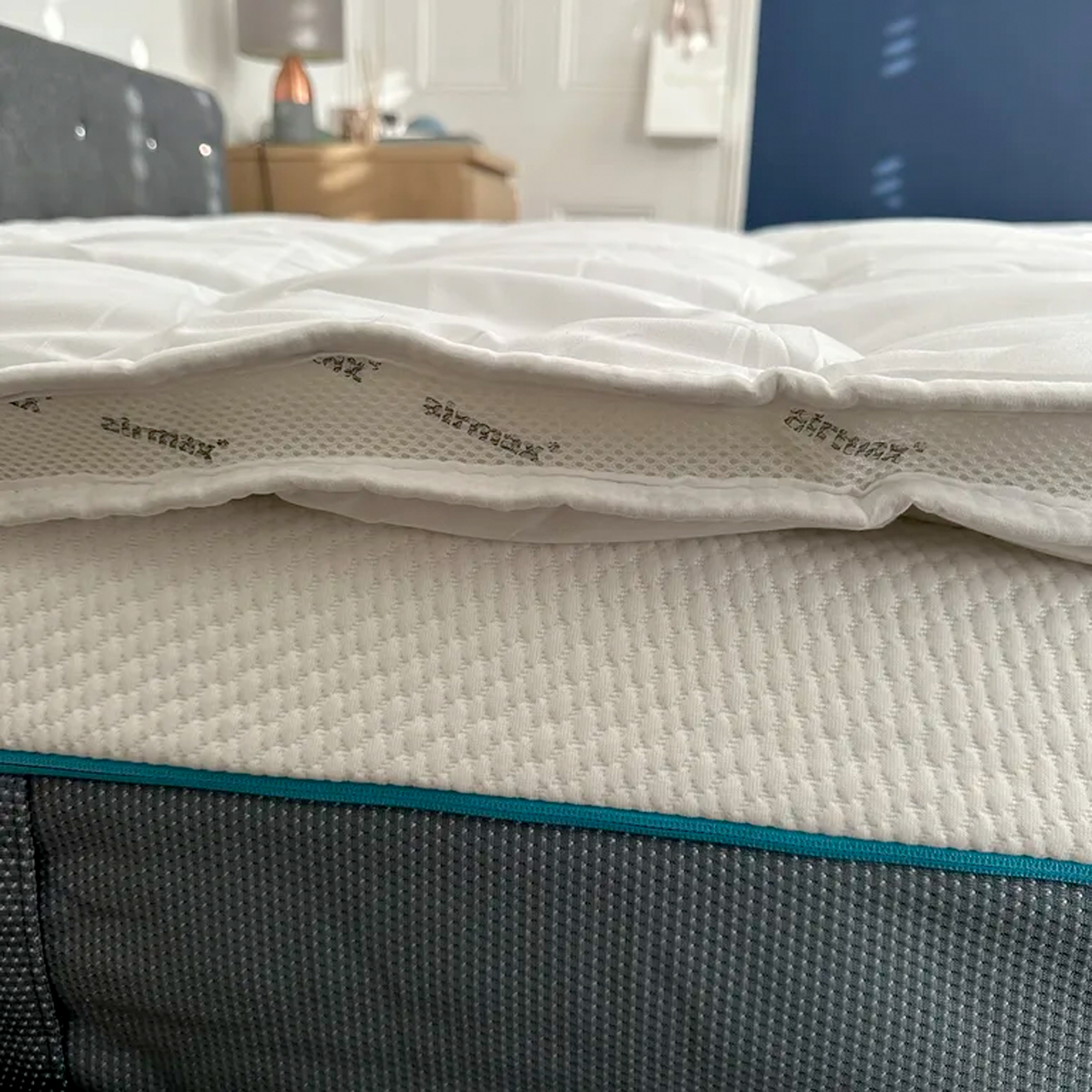 A side view of the Silentnight Airmax mattress topper on a bed showing its mesh side panel