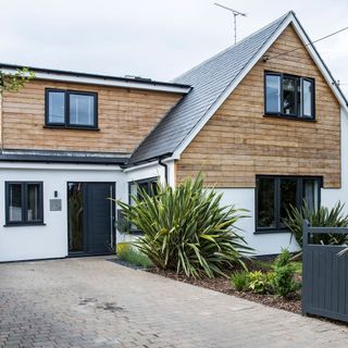house exterior with white wall and slate tile flooring and black door