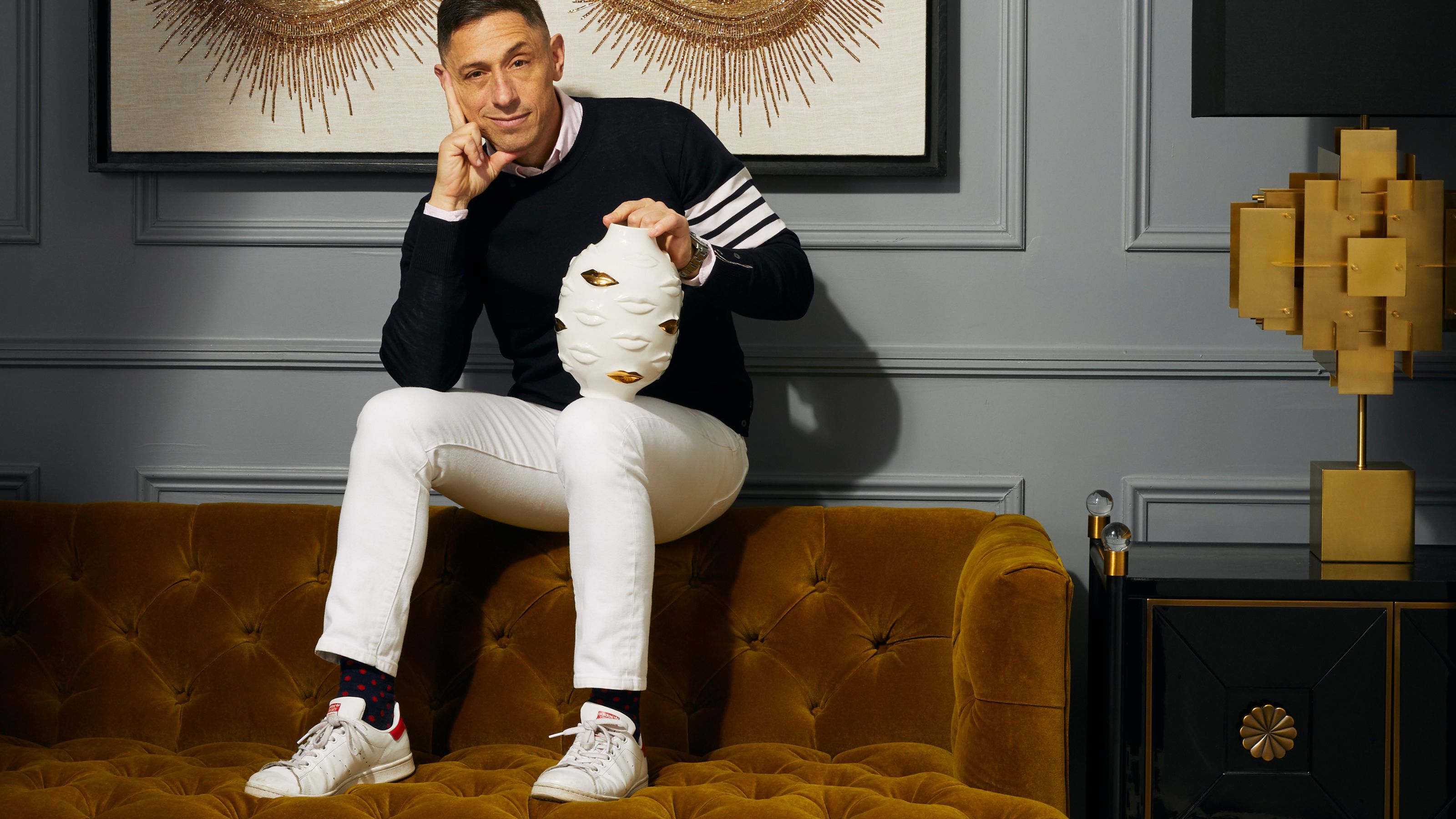 Jonathan Adler sat on the back of a sofa holding a vase