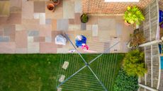 An aerial view of an older woman hanging laundry outside to dry.