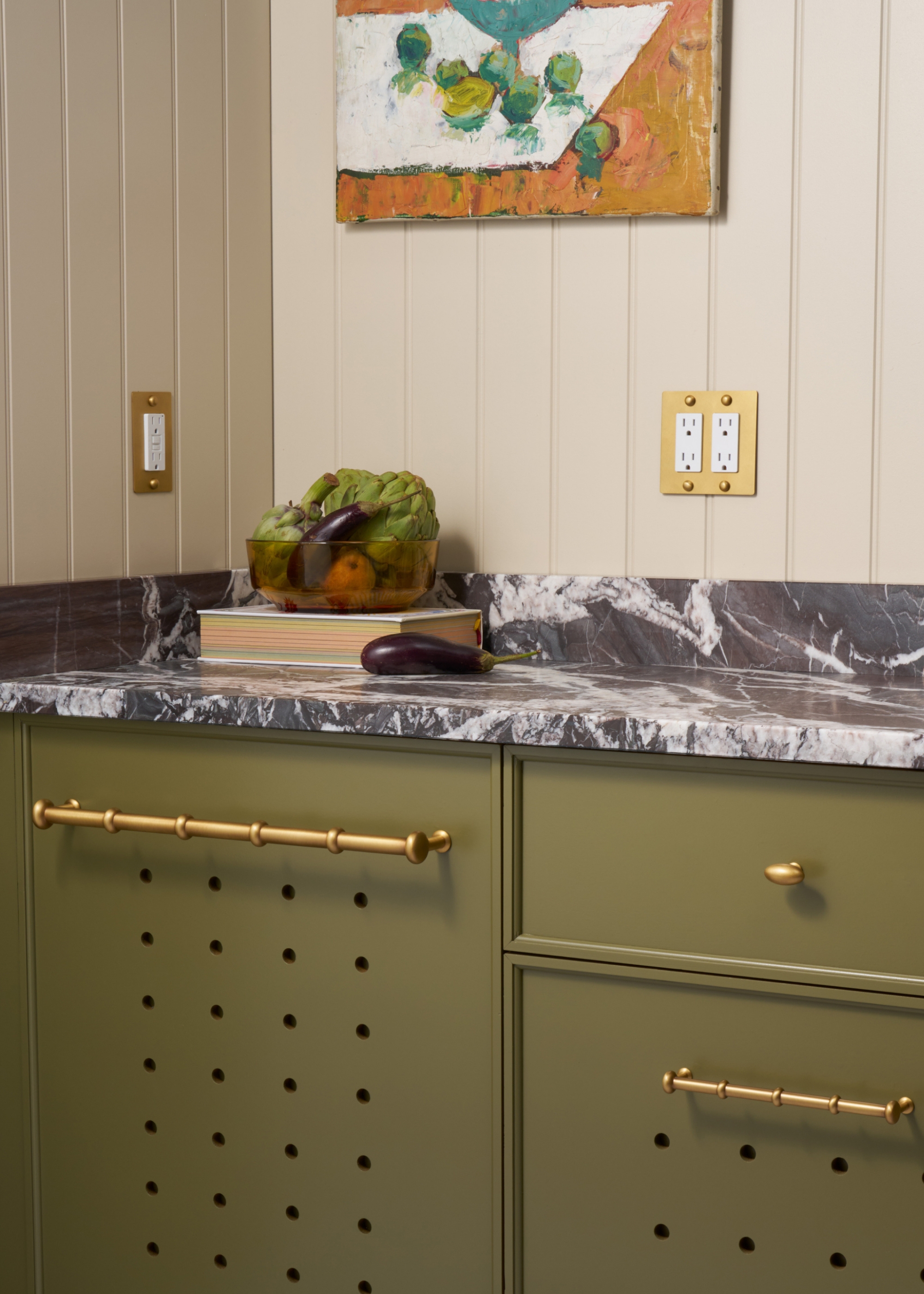 A traditional olive green kitchen with brass hardware and a grey marble worktop