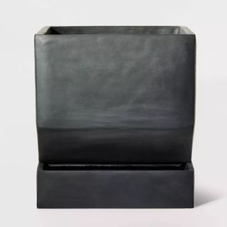 A square black concrete planter in a self watering tray