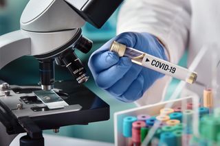 A gloved medical employee conducting research on COVID-19