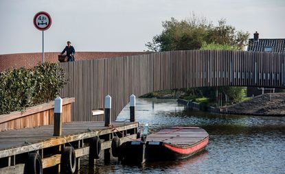 A woman cycling over a bridge constructed from wooden slats