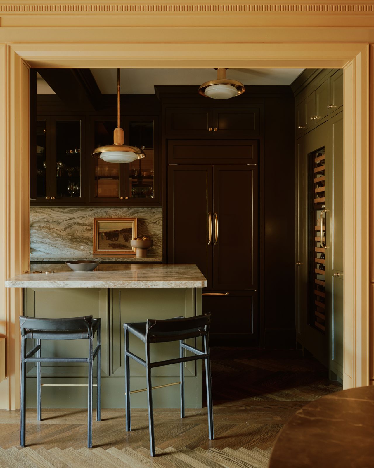 A framed entrance to a galley kitchen complete with two stools.