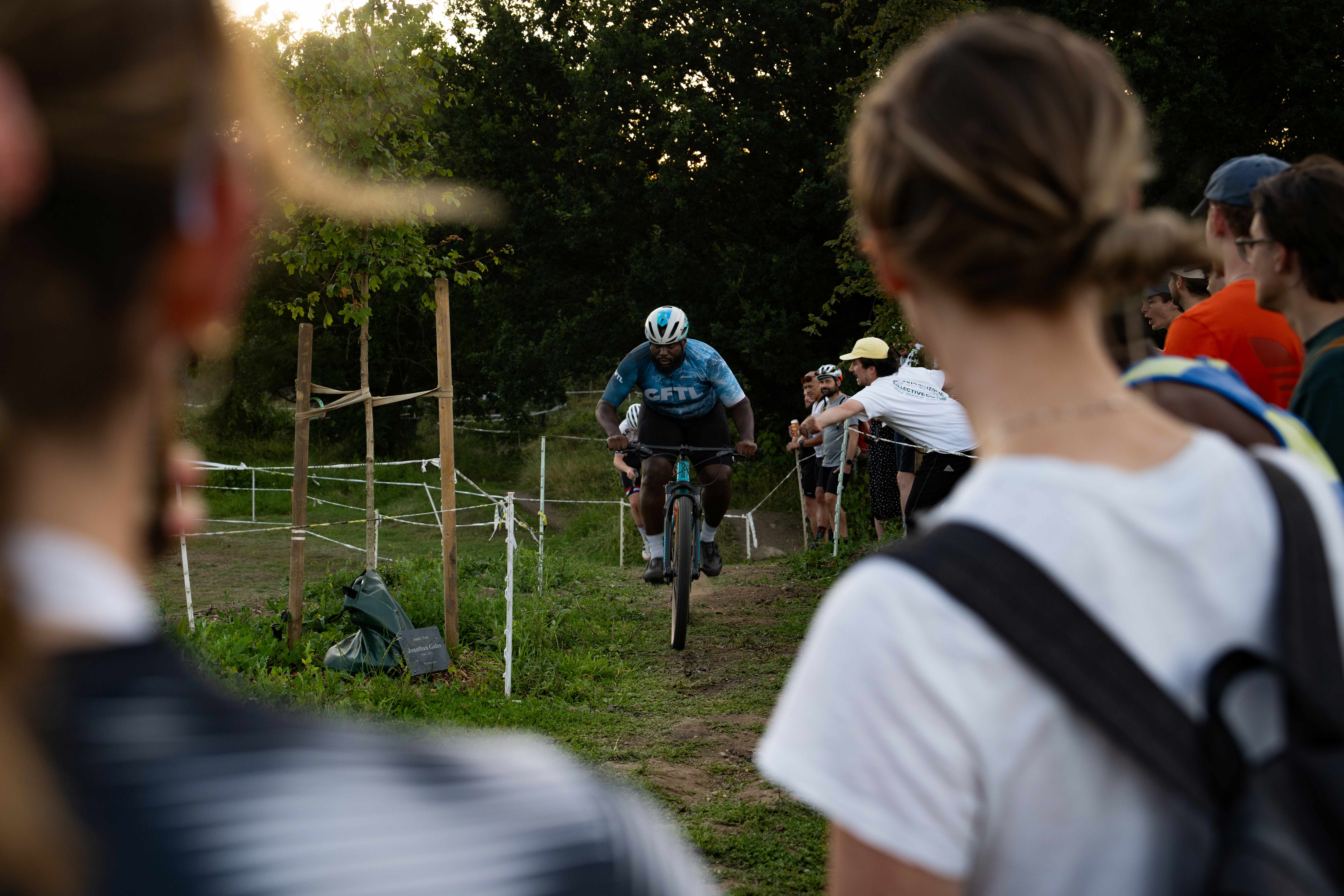 Man cycles uphill next to crowds