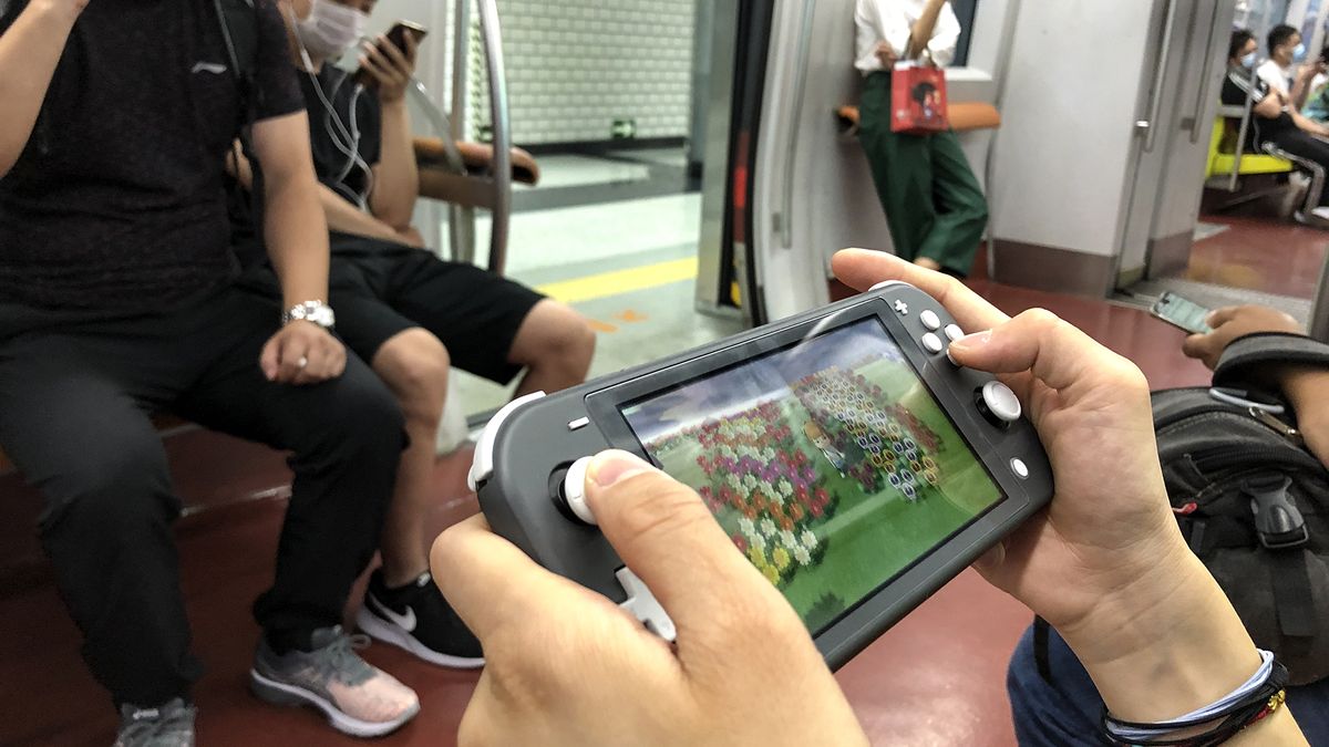 A passenger uses a Nintendo Switch to play video game &#039;Animal Crossing: New Horizons&#039; on a subway train of Beijing Subway Line 1 on June 14, 2020 in Beijing, China.