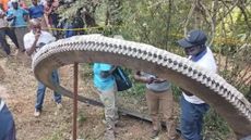 Kenyan men stand around a large metal ring