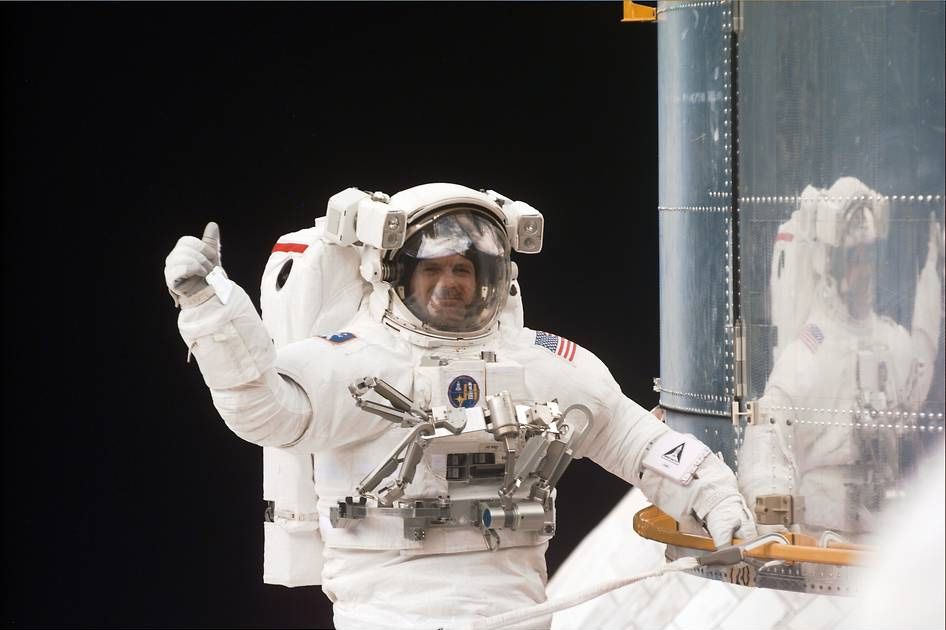 NASA astronaut Steve Smith gives a thumbs-up signal during a spacewalk.