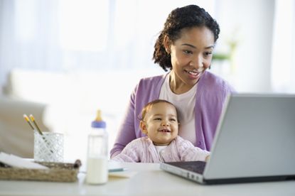 Maternal mental health: A Mixed race woman holding baby and using laptop