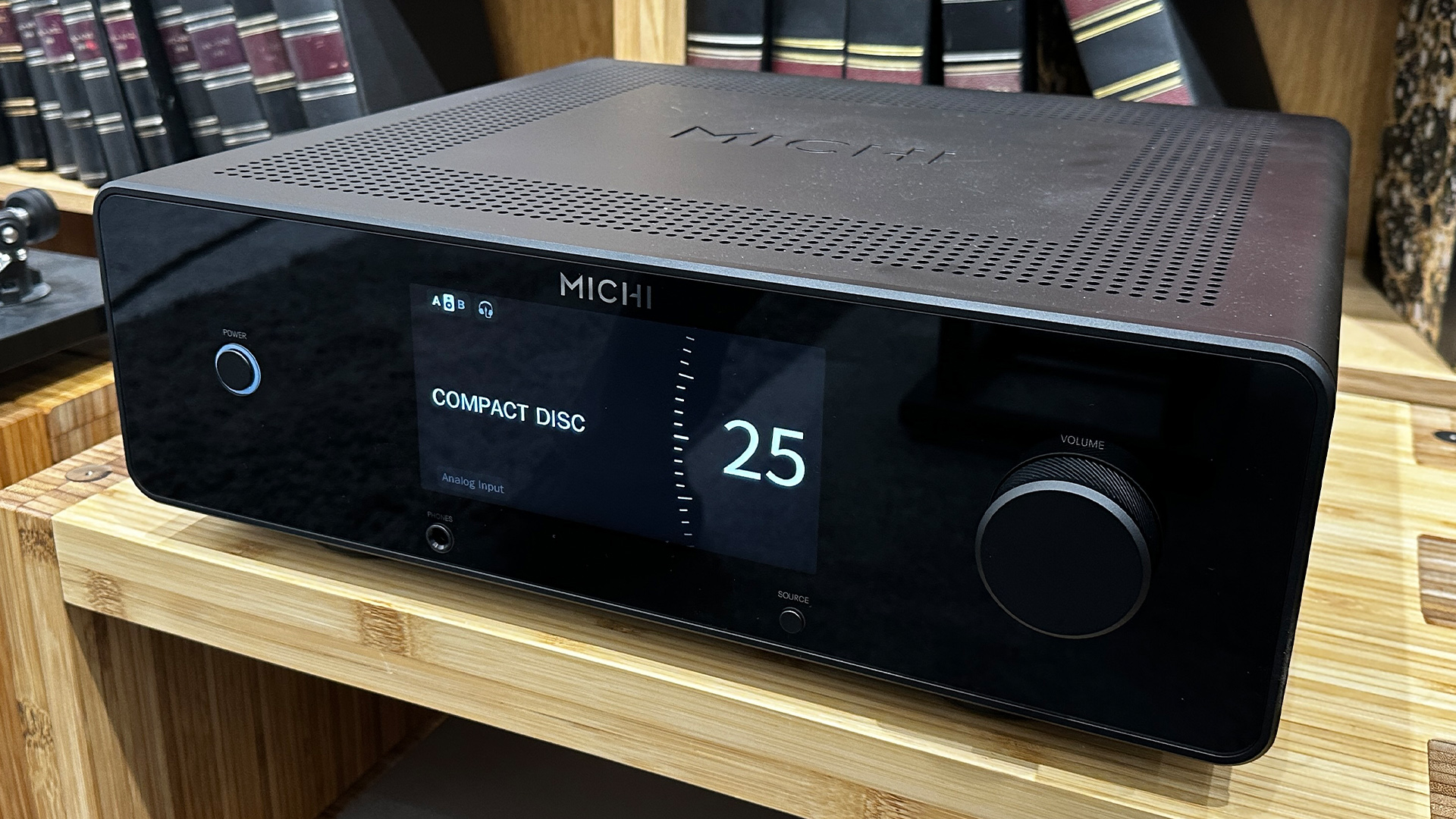 Rotel Michi Prestige X430 integrated amplifier on wooden hi-fi rack in front of bookcase