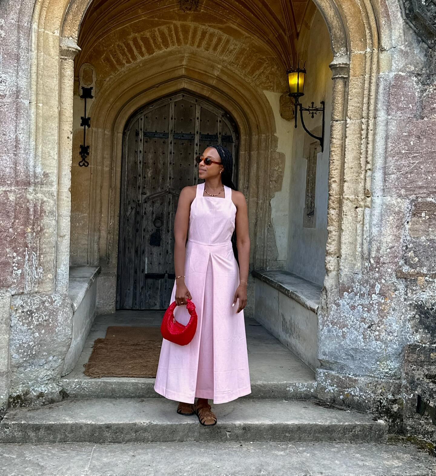 Woman wears pink dress, brown sandals and Red handbag