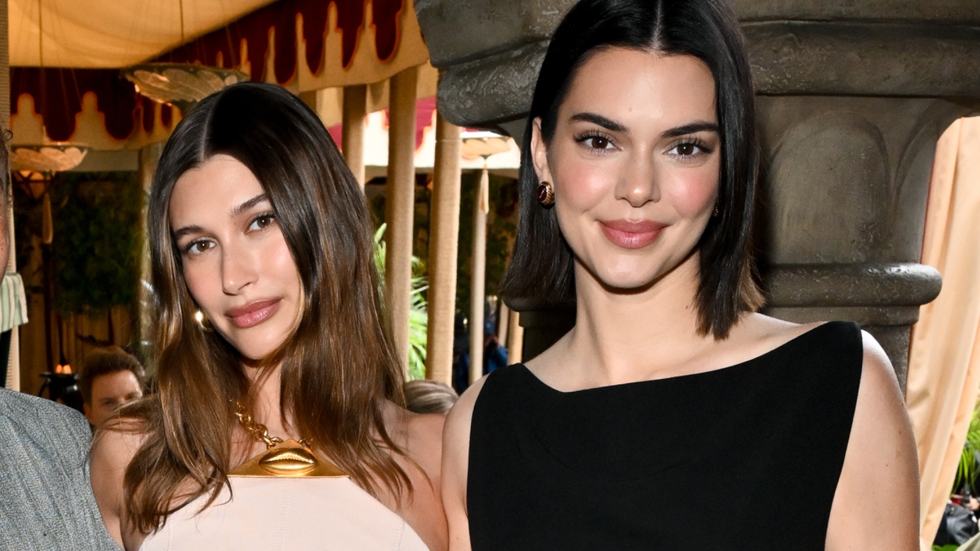Hailey Bieber wears a nude halter dress while Kendall Jenner has a long bob and wears a black dress