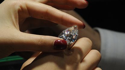 A woman checks the quality of a diamond at the Hong Kong Jewellery and Gem Fair in Hong Kong on September 22, 2009.The seven day event which began on September 21, will showcase raw materials