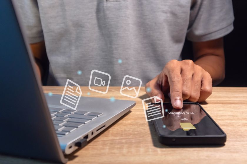 A man transfer files between mobile phone and laptop.
