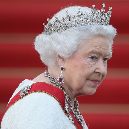 Queen Elizabeth wearing a white dress, red sash and tiara
