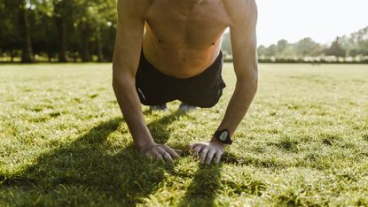 Man doing a plank outside on grass