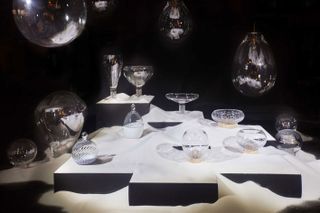 Multiple shaped glass bowls and sculptures against a black background