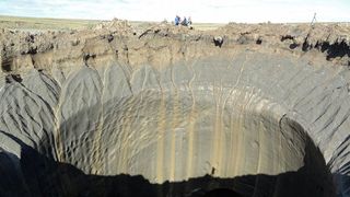 a deep crater in a grassy tundra