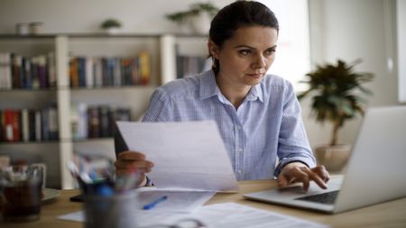 Woman looking at her bills and her laptop 