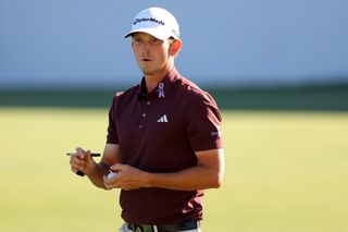 Jacob Bridgeman signs a golf ball with a pen