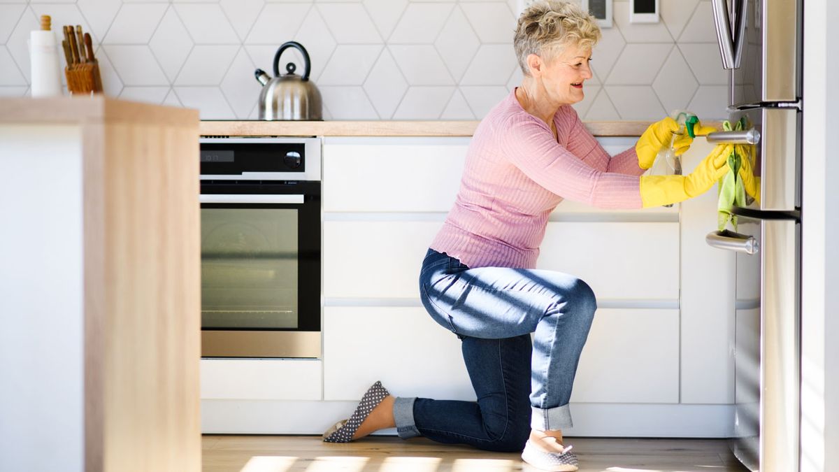 How to clean a fridge: Image shows a woman cleaning her fridge.