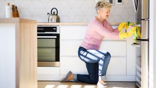 How to clean a fridge: Image shows a woman cleaning her fridge.
