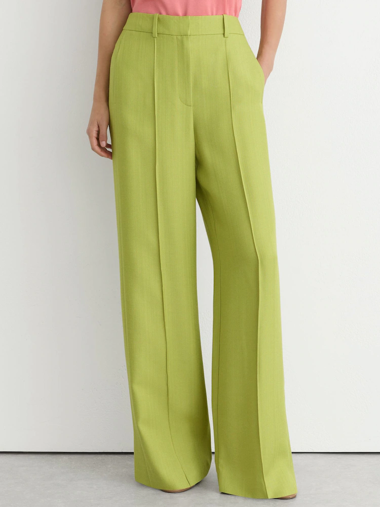 A model wearing apple green Reiss trousers