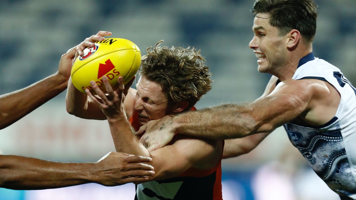 Lachie Whitfield of the Giants is tackled by Geelong Cats player