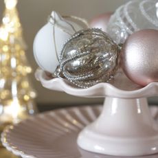 Christmas baubles on pink cake stand.